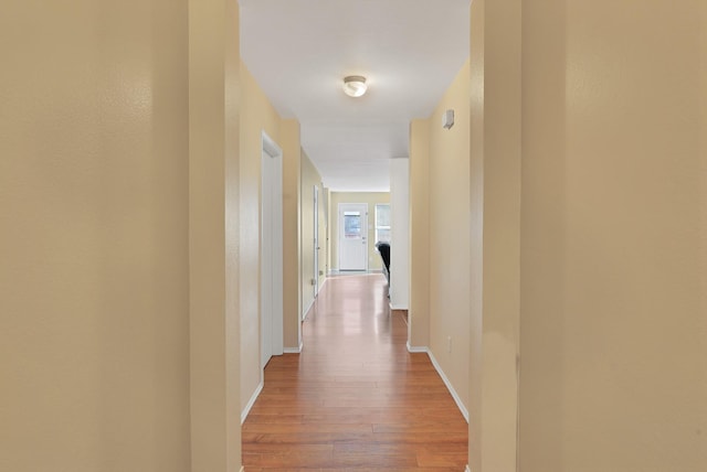 hall with light wood-style flooring and baseboards