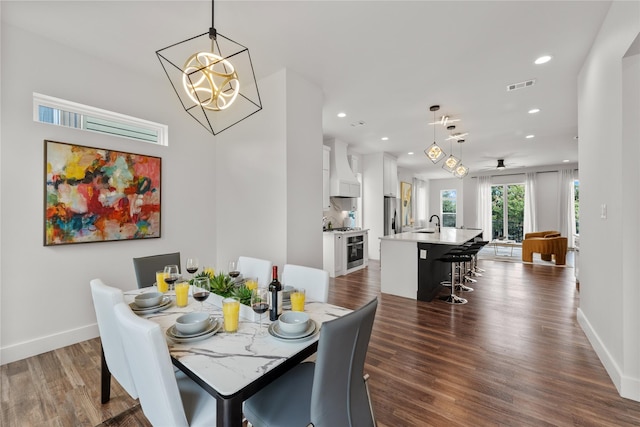 dining room featuring ceiling fan with notable chandelier, dark wood-type flooring, and sink