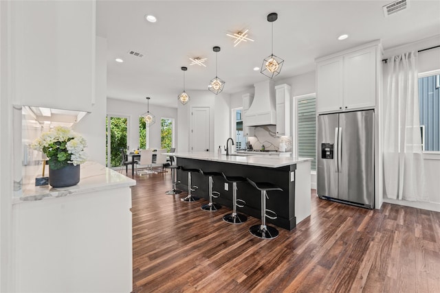 kitchen with white cabinetry, dark hardwood / wood-style flooring, stainless steel fridge, pendant lighting, and custom exhaust hood