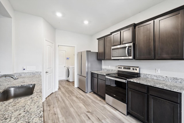 kitchen with light stone counters, sink, light hardwood / wood-style floors, and appliances with stainless steel finishes