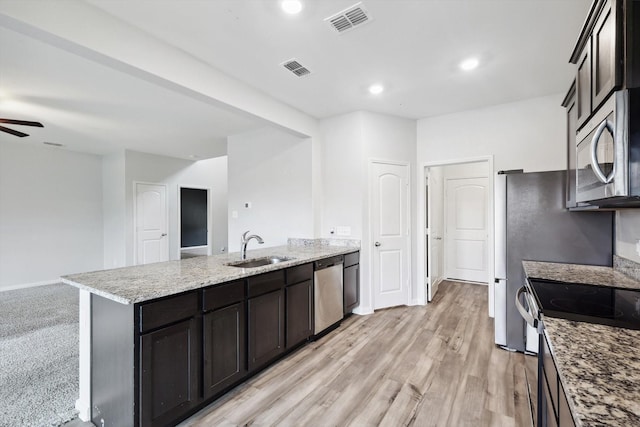 kitchen featuring sink, ceiling fan, stainless steel appliances, a center island with sink, and light wood-type flooring