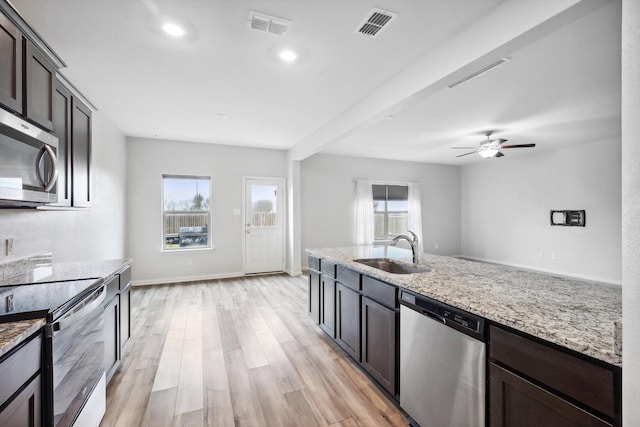 kitchen featuring sink, dark brown cabinets, light wood-type flooring, appliances with stainless steel finishes, and light stone countertops