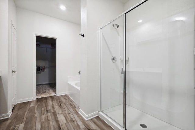 bathroom with hardwood / wood-style floors and independent shower and bath