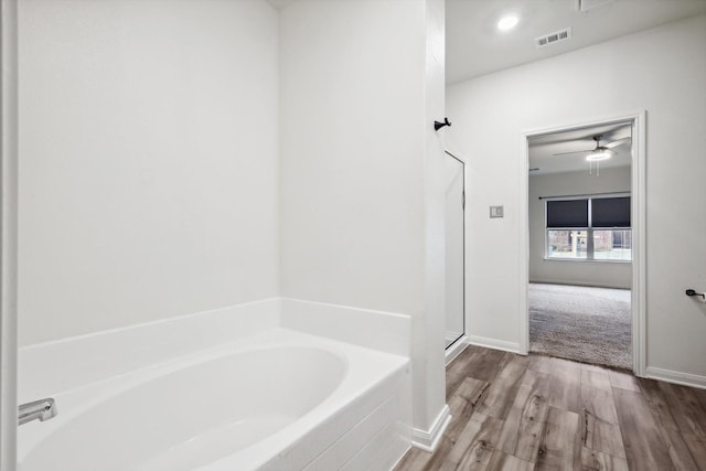 bathroom featuring ceiling fan, separate shower and tub, and wood-type flooring