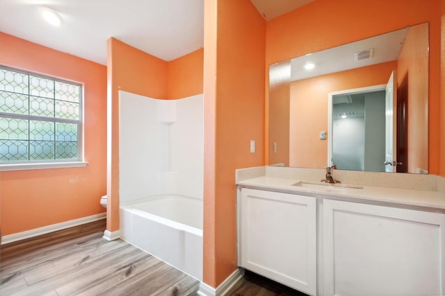 full bathroom featuring wood-type flooring, shower / bathing tub combination, vanity, and toilet