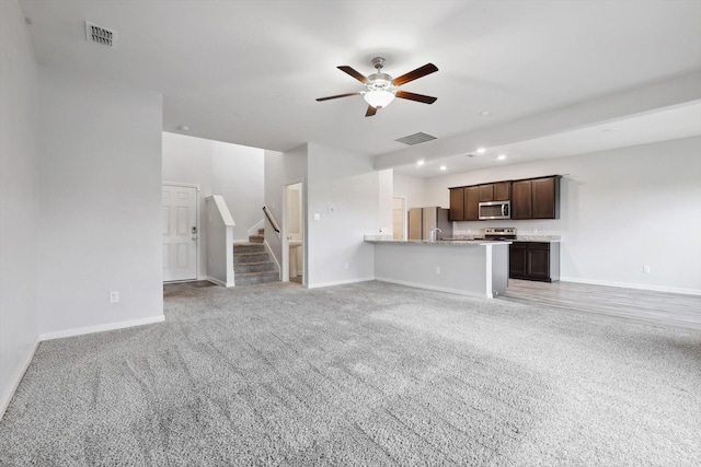 unfurnished living room featuring light colored carpet and ceiling fan