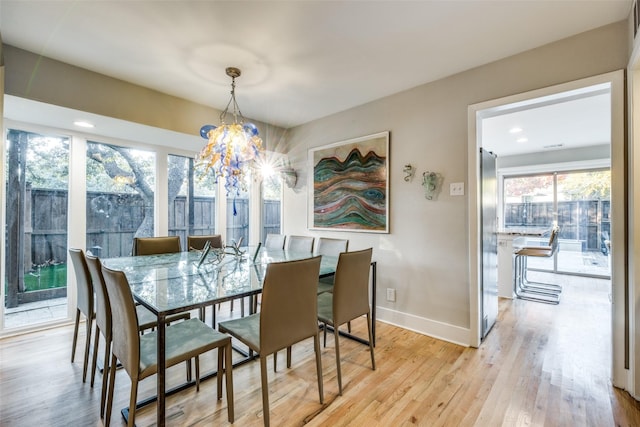 dining area with light hardwood / wood-style flooring and an inviting chandelier