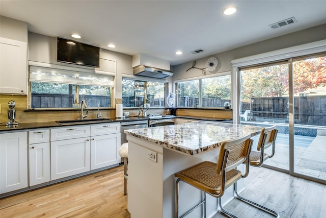 kitchen featuring backsplash, light hardwood / wood-style floors, sink, and dark stone counters