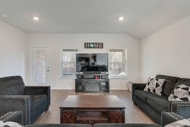 living room featuring plenty of natural light, wood-type flooring, and vaulted ceiling