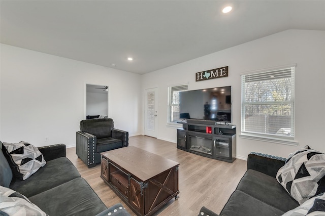 living room featuring light hardwood / wood-style floors, ceiling fan, and lofted ceiling