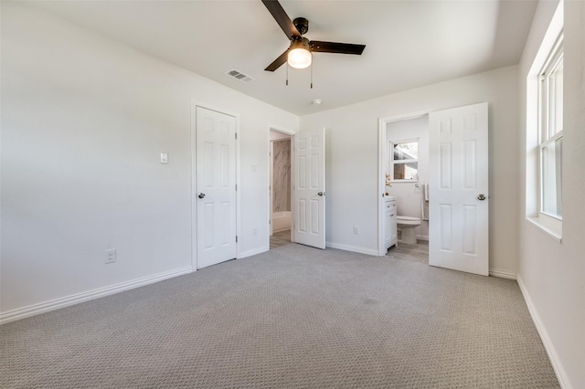 unfurnished bedroom with ensuite bath, ceiling fan, a closet, and light colored carpet