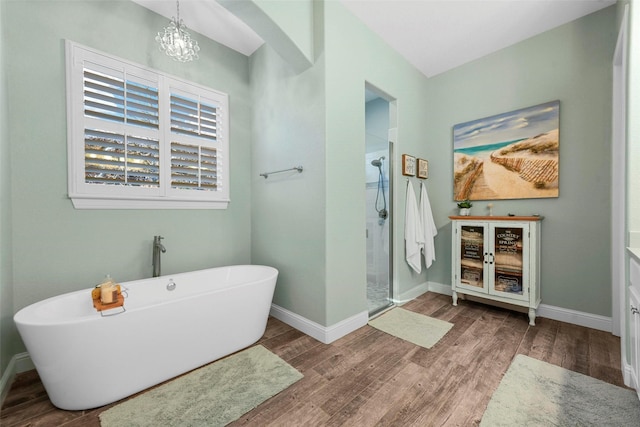 bathroom featuring plus walk in shower, a notable chandelier, and hardwood / wood-style flooring