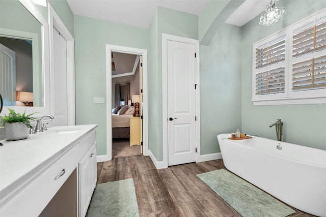 bathroom with wood-type flooring, vanity, a tub, and a notable chandelier