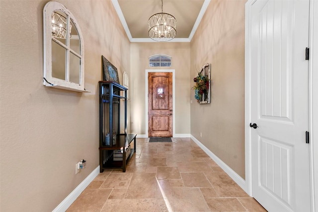 entryway with an inviting chandelier, a high ceiling, and ornamental molding