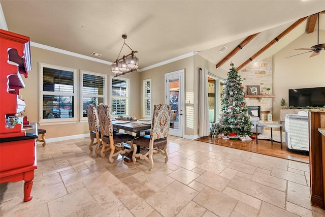 dining room featuring vaulted ceiling with beams, ceiling fan, a large fireplace, and crown molding