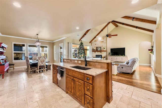 kitchen featuring dishwasher, sink, vaulted ceiling with beams, a kitchen island with sink, and a fireplace