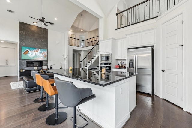 kitchen with white cabinetry, appliances with stainless steel finishes, a towering ceiling, and dark hardwood / wood-style flooring