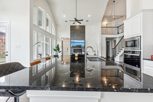 kitchen with dark stone countertops, pendant lighting, stainless steel microwave, and oven