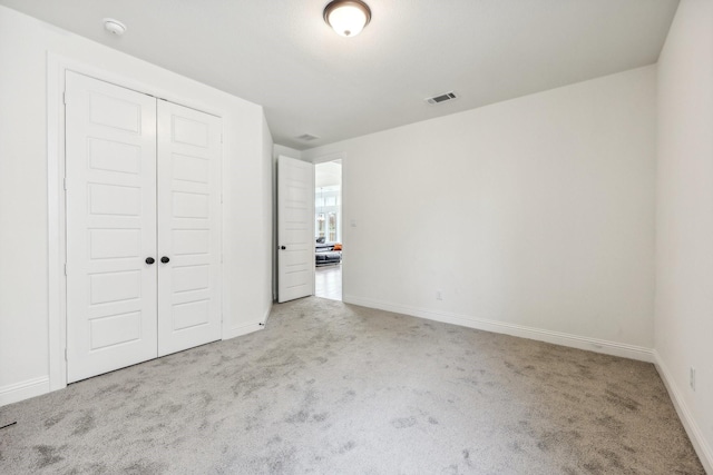 unfurnished bedroom featuring light carpet and a closet