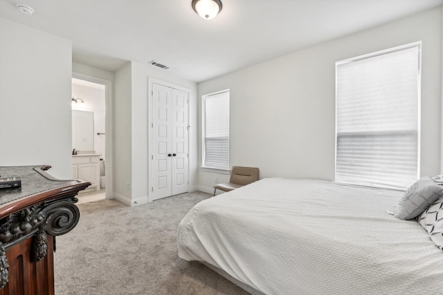 carpeted bedroom featuring ensuite bath and a closet