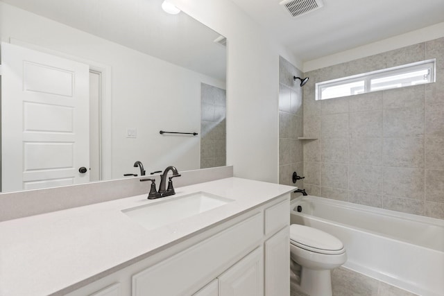 full bathroom with tiled shower / bath, vanity, and toilet