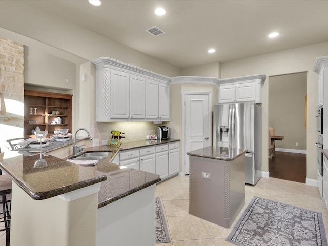 kitchen with sink, a breakfast bar area, white cabinetry, appliances with stainless steel finishes, and kitchen peninsula