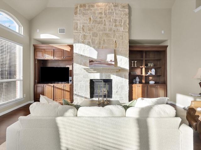 living room with a stone fireplace, dark wood-type flooring, and high vaulted ceiling