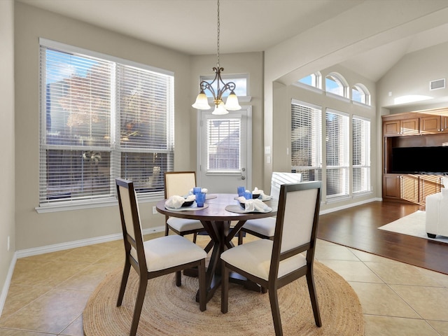 tiled dining room featuring a notable chandelier and high vaulted ceiling