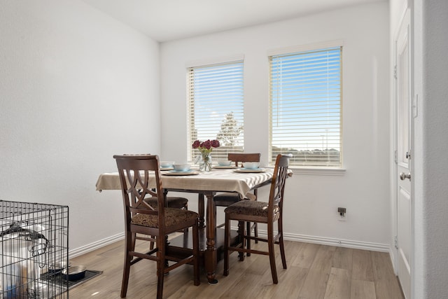 dining space with light wood-style flooring and baseboards