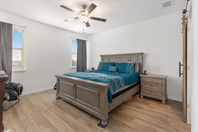 bedroom with visible vents, multiple windows, light wood-style floors, and baseboards