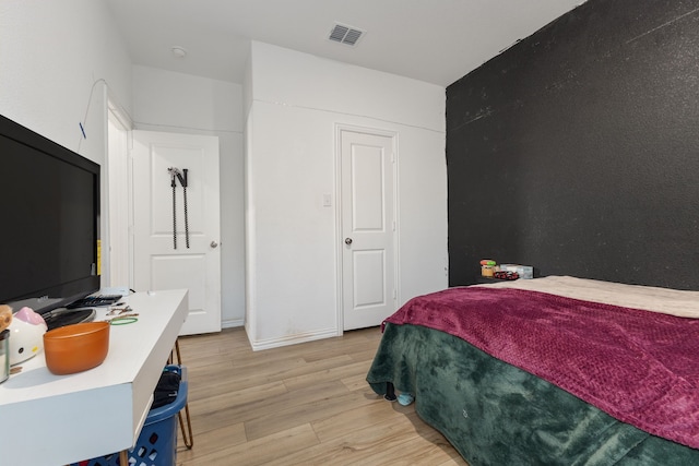 bedroom with light wood-style floors and visible vents