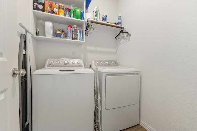 laundry area with washing machine and clothes dryer, laundry area, baseboards, and wood finished floors