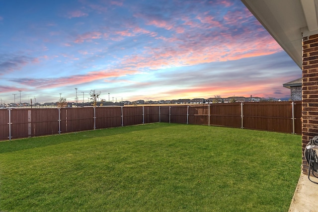 yard at dusk featuring a fenced backyard