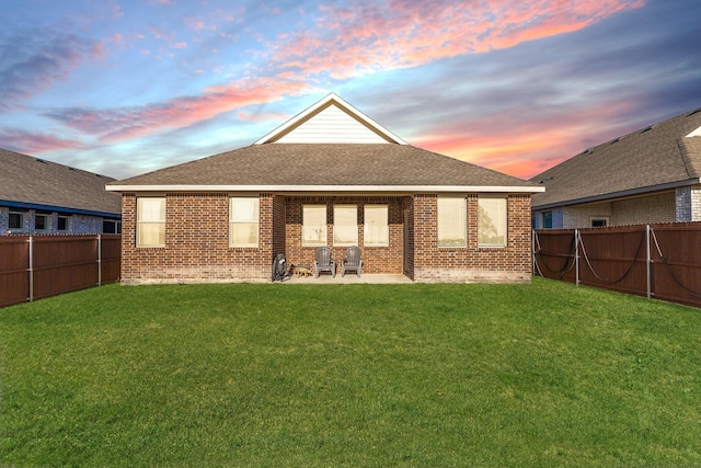 rear view of house featuring a yard, brick siding, a fenced backyard, and a patio area