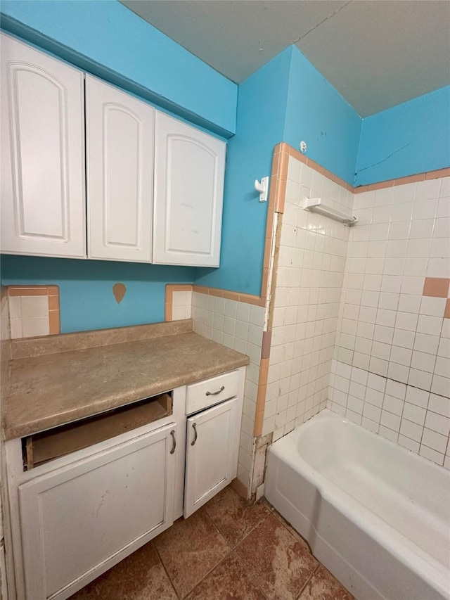 bathroom with tile patterned flooring, tiled shower / bath, and tile walls