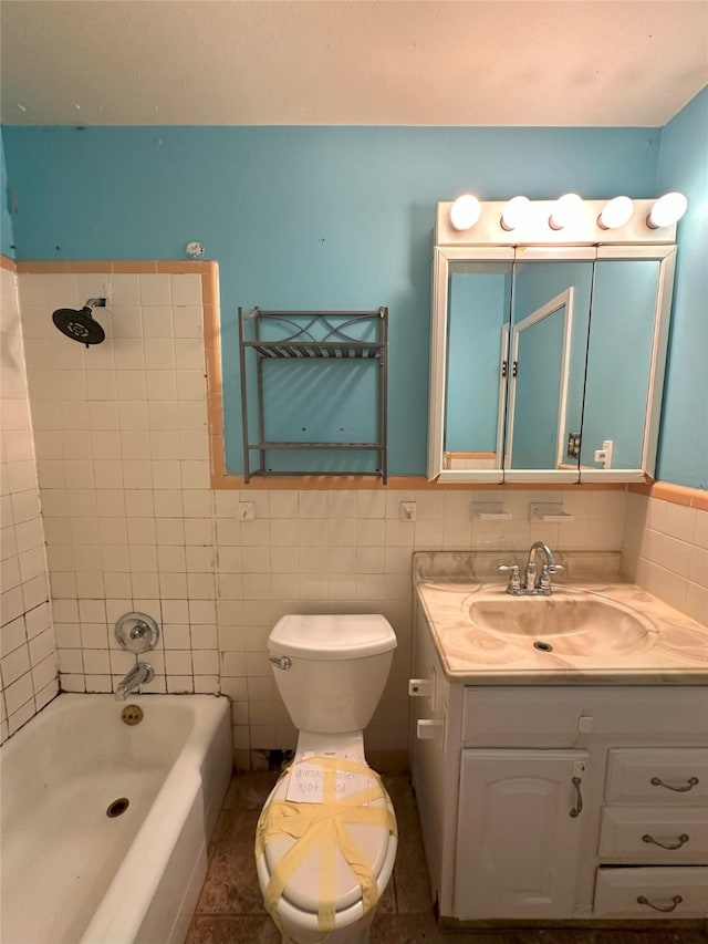 full bathroom featuring tile patterned floors, vanity, tiled shower / bath combo, tile walls, and toilet