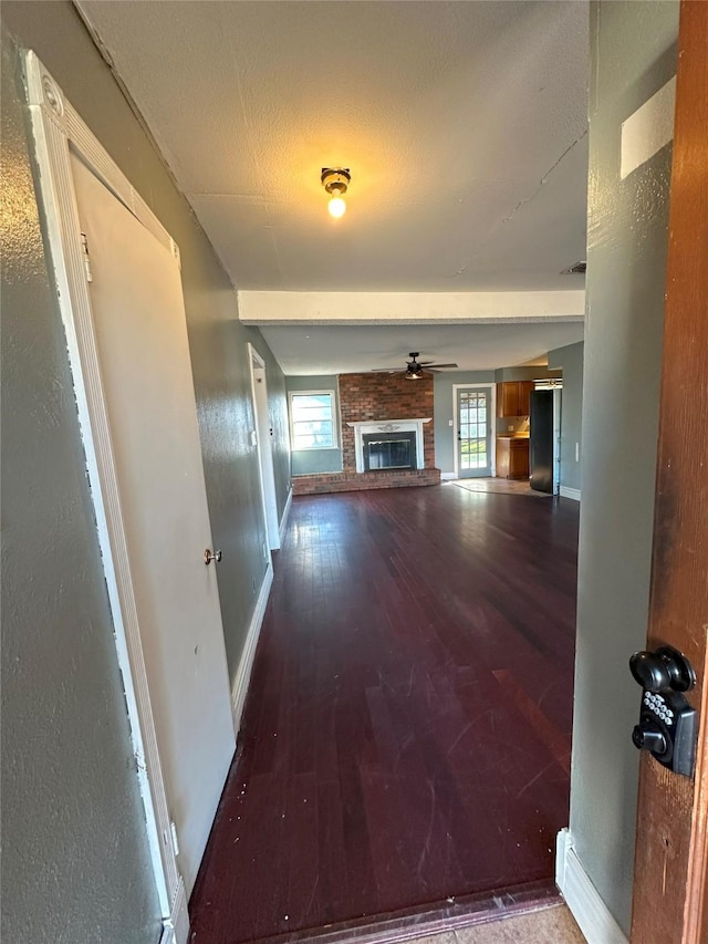 unfurnished living room with ceiling fan, wood-type flooring, and a brick fireplace