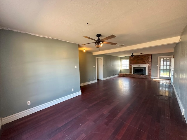 unfurnished living room featuring dark hardwood / wood-style floors, a brick fireplace, and plenty of natural light