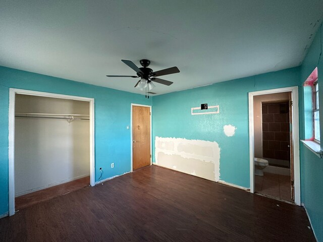 unfurnished bedroom featuring connected bathroom, dark hardwood / wood-style floors, a closet, and ceiling fan