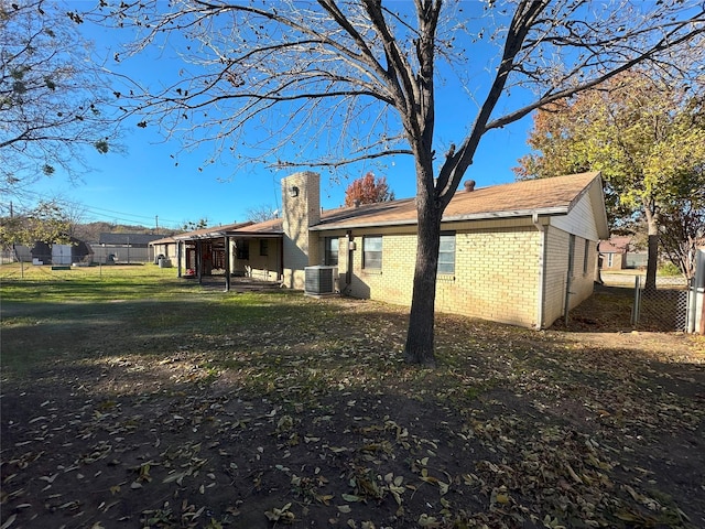 rear view of house featuring central AC unit and a lawn