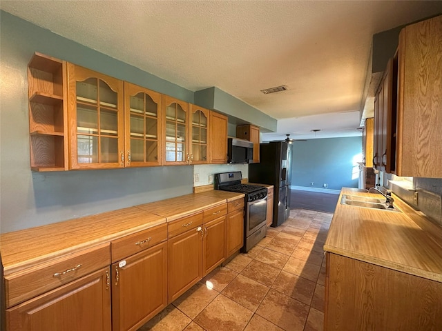 kitchen with a textured ceiling, ceiling fan, sink, black appliances, and light tile patterned floors