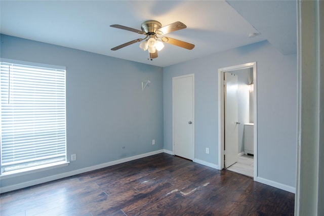 unfurnished bedroom with dark hardwood / wood-style flooring, ensuite bath, multiple windows, and ceiling fan