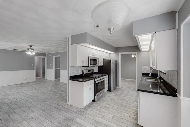 kitchen featuring sink, ceiling fan, appliances with stainless steel finishes, backsplash, and white cabinets