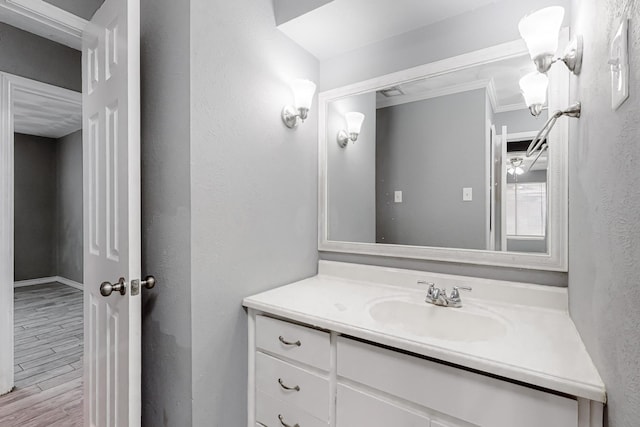 bathroom with crown molding, vanity, and hardwood / wood-style floors