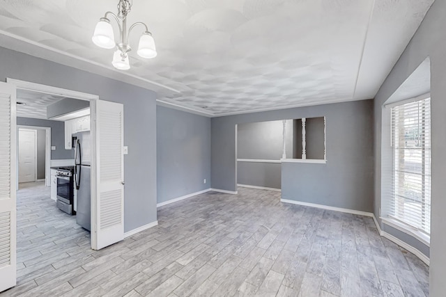 spare room featuring a chandelier and light hardwood / wood-style flooring