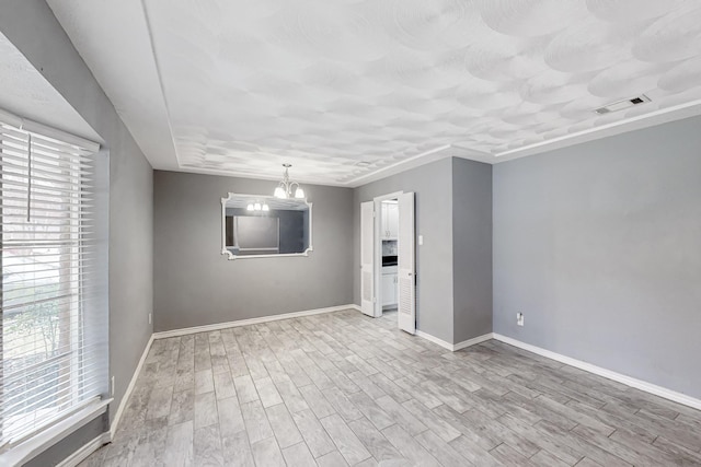 unfurnished room featuring an inviting chandelier and light wood-type flooring