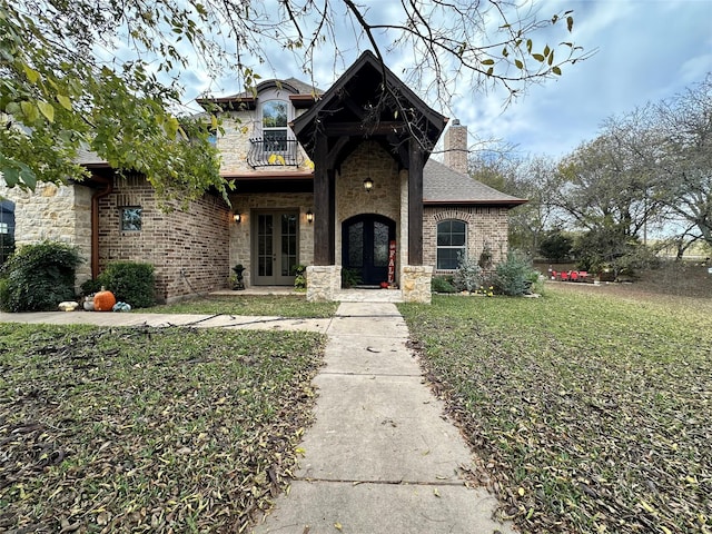 view of front of house with a front yard, french doors, and a balcony