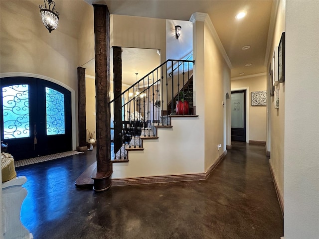 foyer entrance with a high ceiling, french doors, and ornamental molding