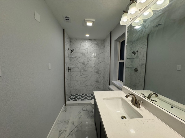 bathroom with a tile shower and vanity