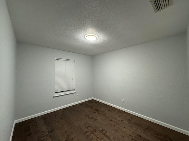 spare room featuring a textured ceiling and dark hardwood / wood-style flooring